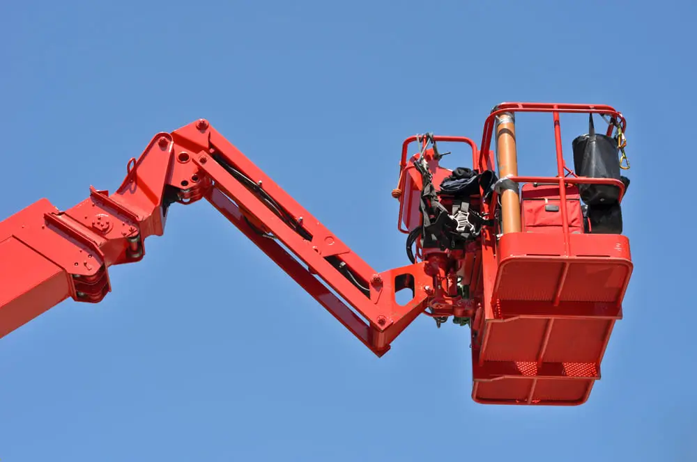Red hydraulic construction cradle against the blue sky.