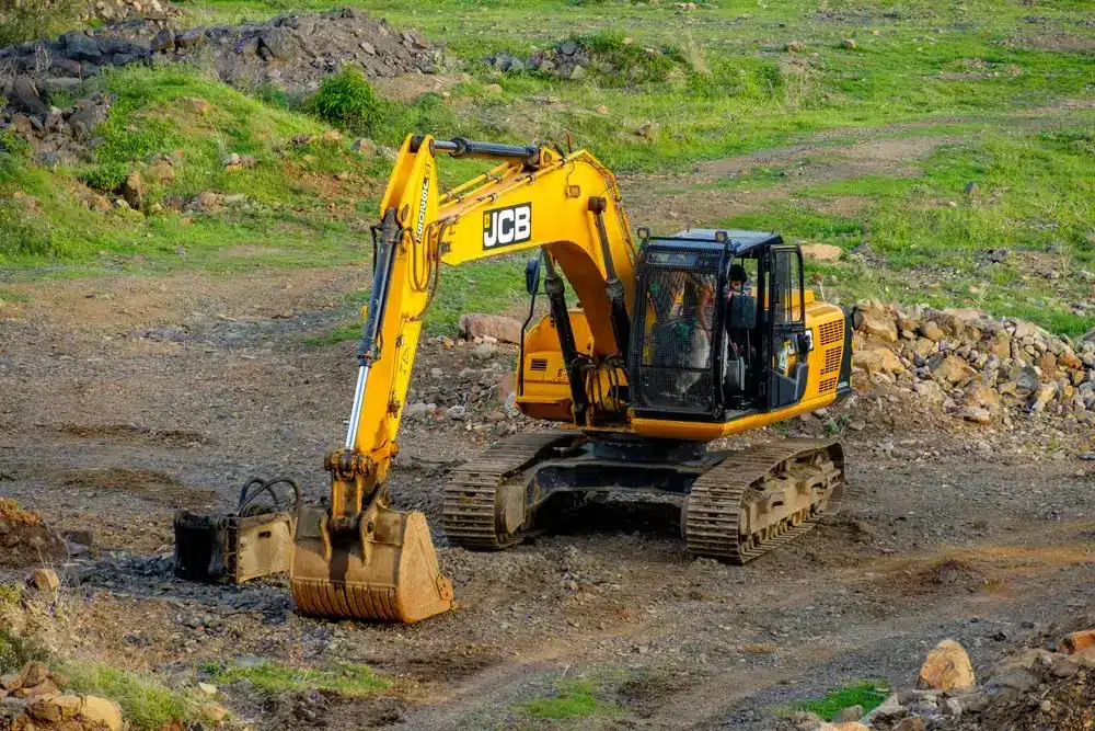Excavator machine at work in an open field.